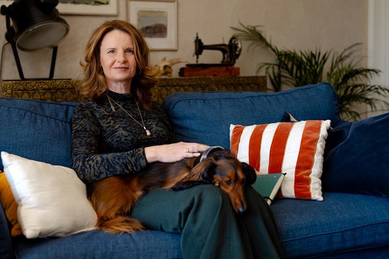 Beile Grünbaum on her sofa with her dog, writing about loss aversion and money stress